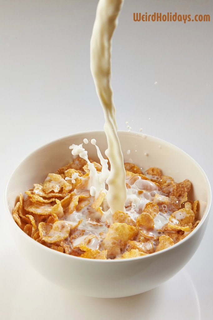 bowl of cornflakes with milk being poured into the white bowl