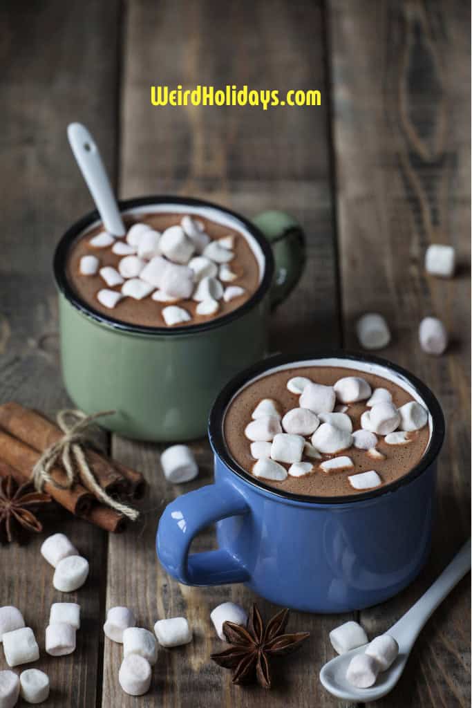 2 mugs of hot chocoloate with marshmallows and a spoon