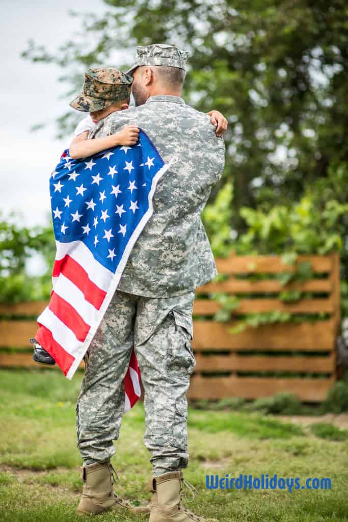 boy hugging a soldier holding an american flag