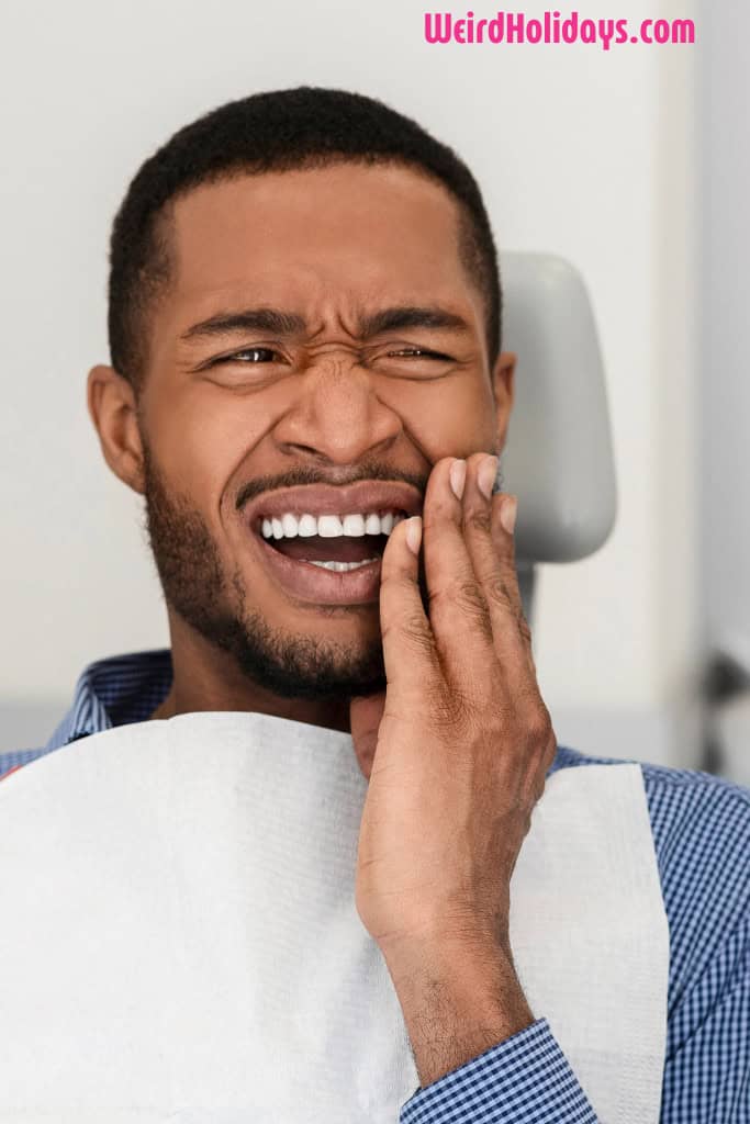 man holding his face in pain at the dentist