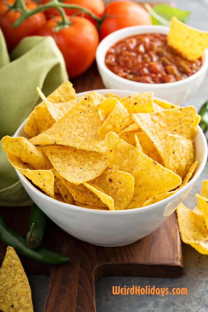 bowl of nachos with tomatoes and salsa next to it