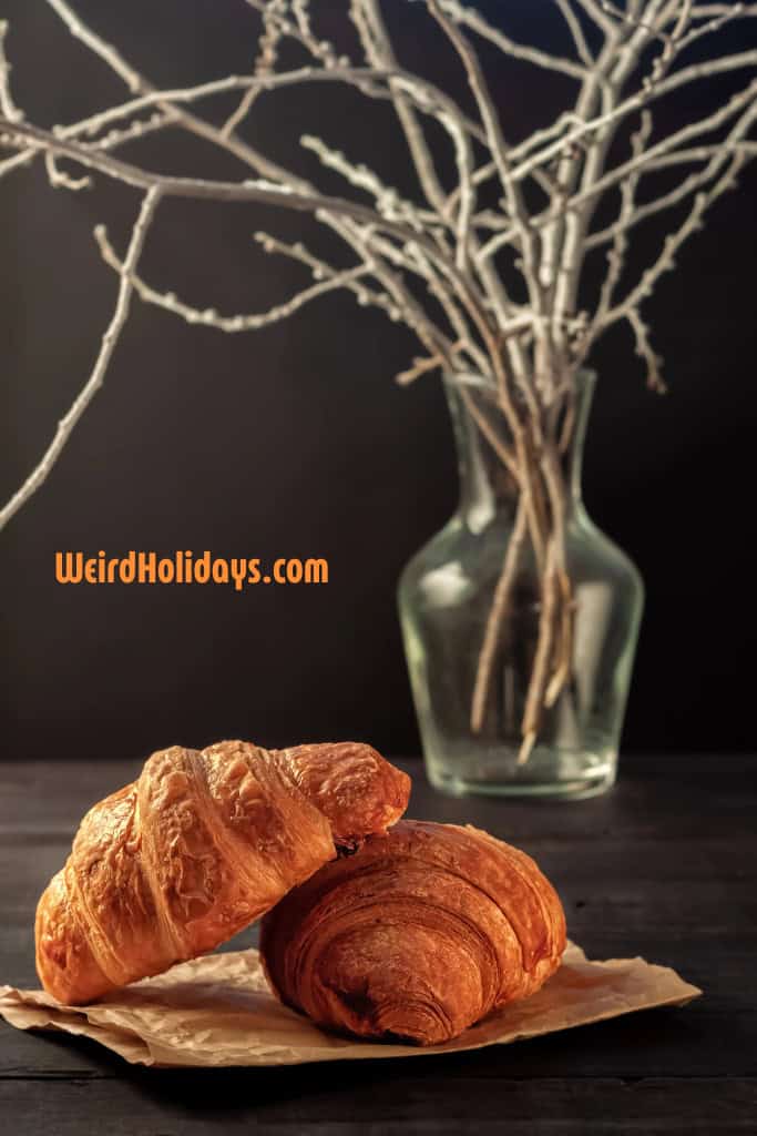 2 croissants on a plate with a black background