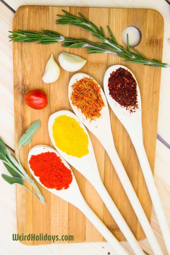 4 wooden spoons on a wooden chopping board with different colored spices