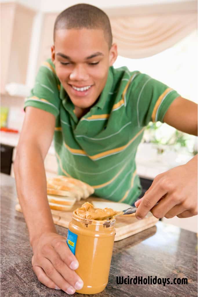 teenage boy using peanut butter on his sandwich