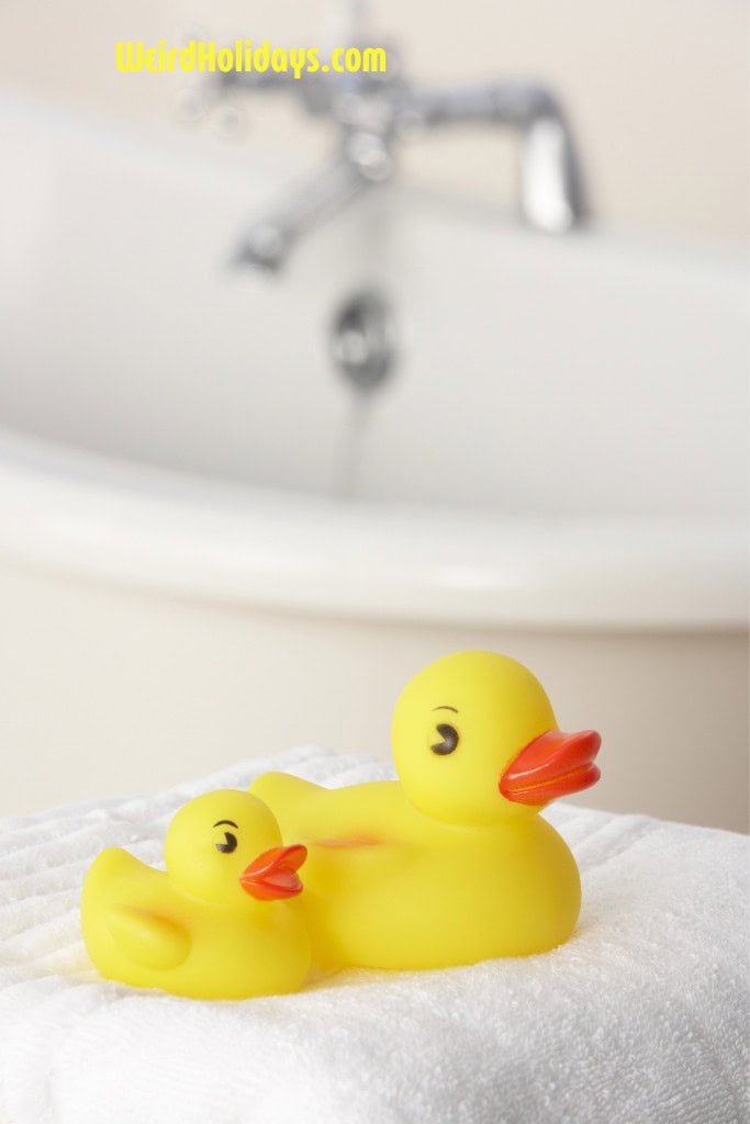 2 rubber ducks sitting on a white towel next to a bath