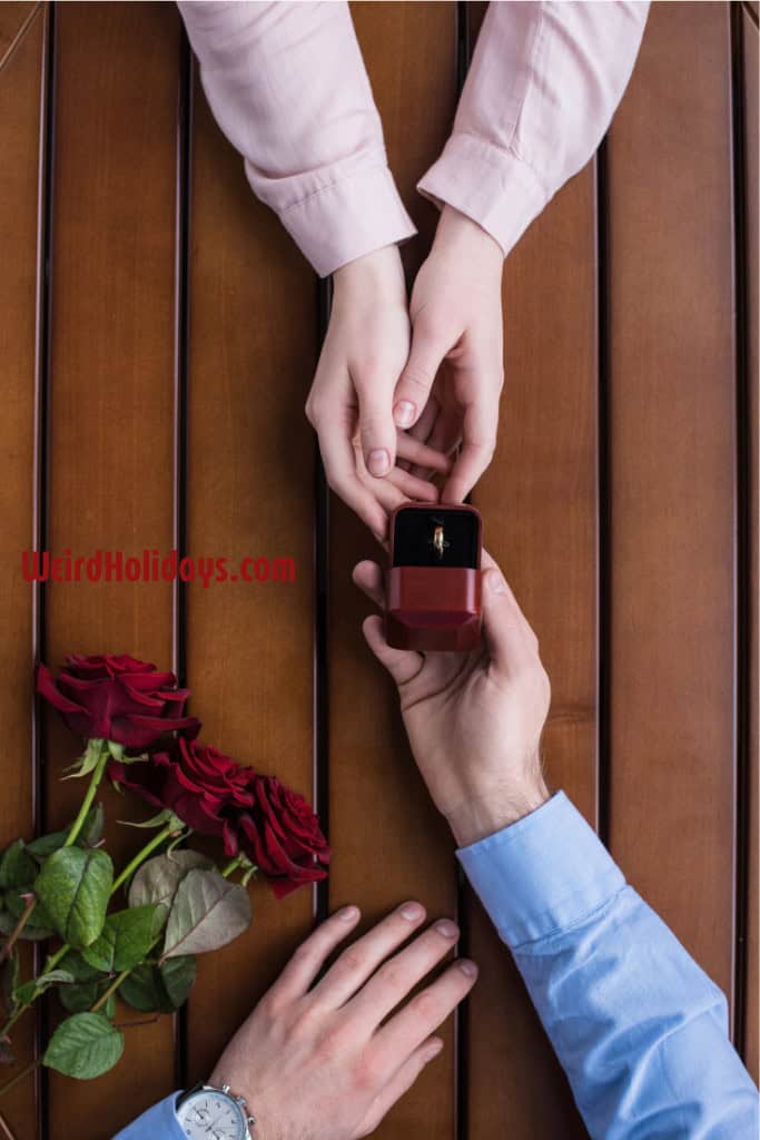 man handing a woman an engagement ring over a table