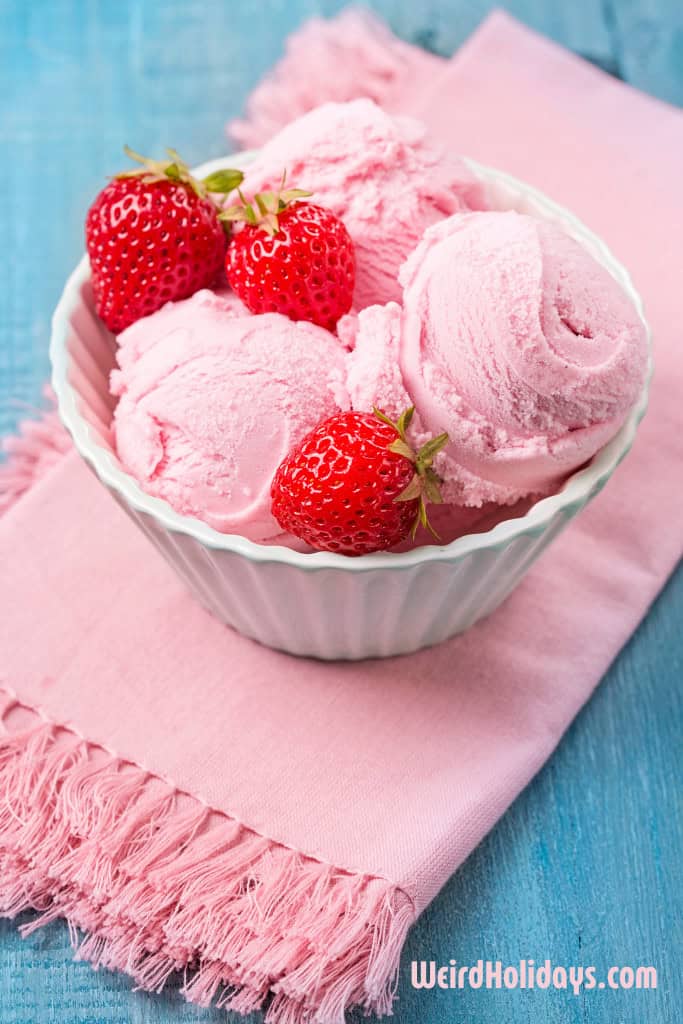 strawberry ice cream in a bowl with whole strawberries