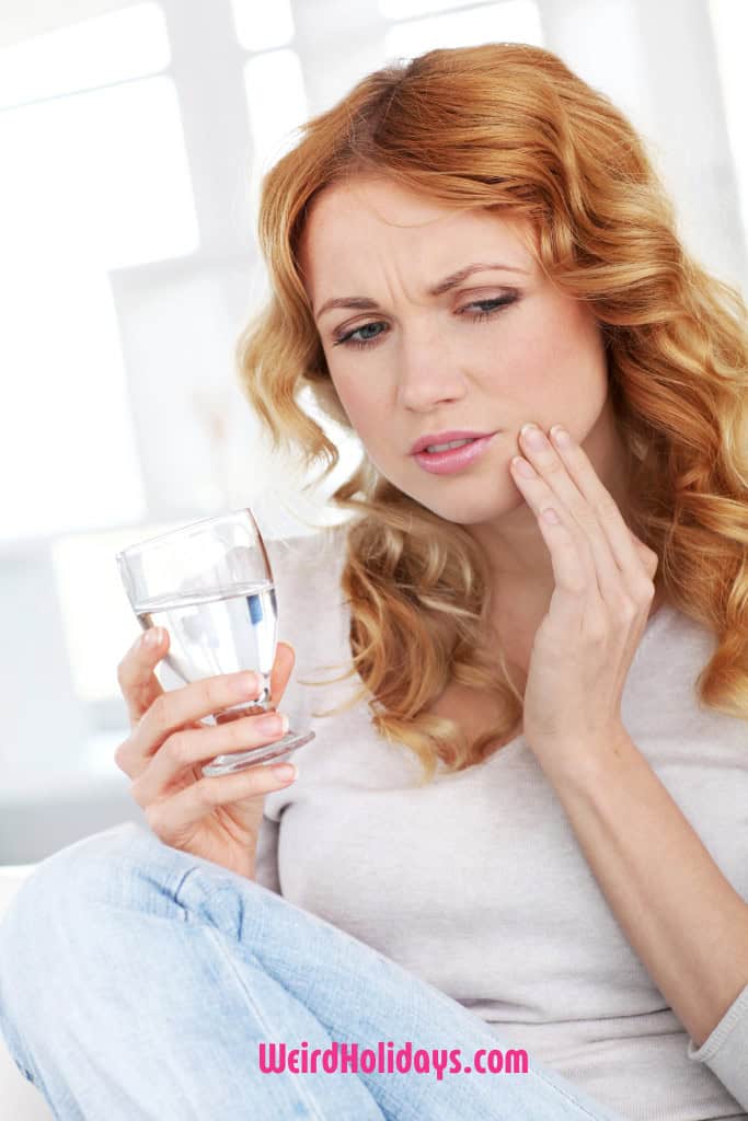 woman with a toothache holding a glass of water