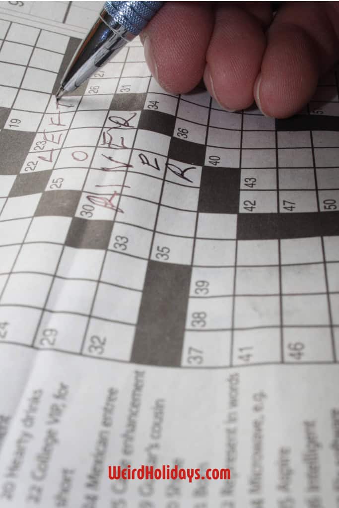 someone completing a crossword puzzle from a newspaper